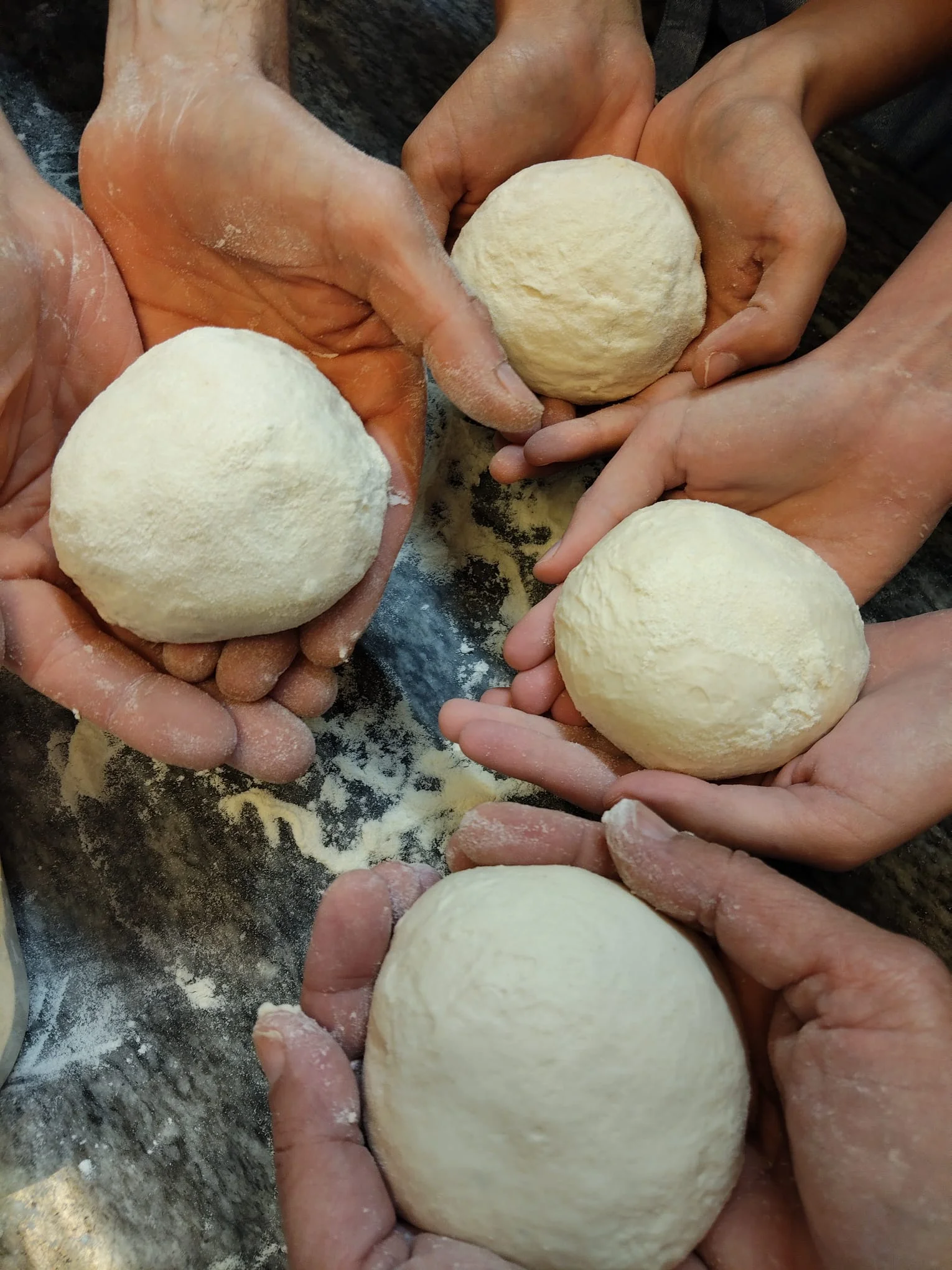 Le mani degli allievi — pasta fresca preparata insieme Mani degli allievi che mostrano le palline di pasta fresca preparate insieme durante il corso
