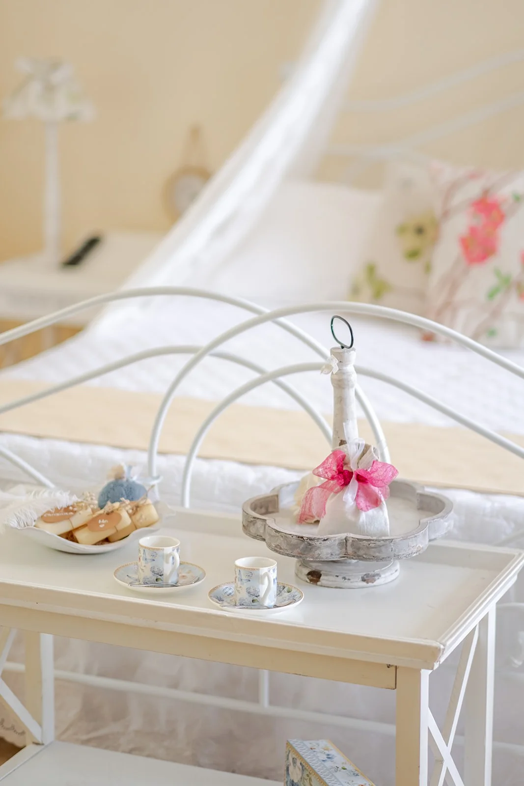Vassoio del benvenuto posato sul letto: tazzine, biscotti e dolcetto coordinato