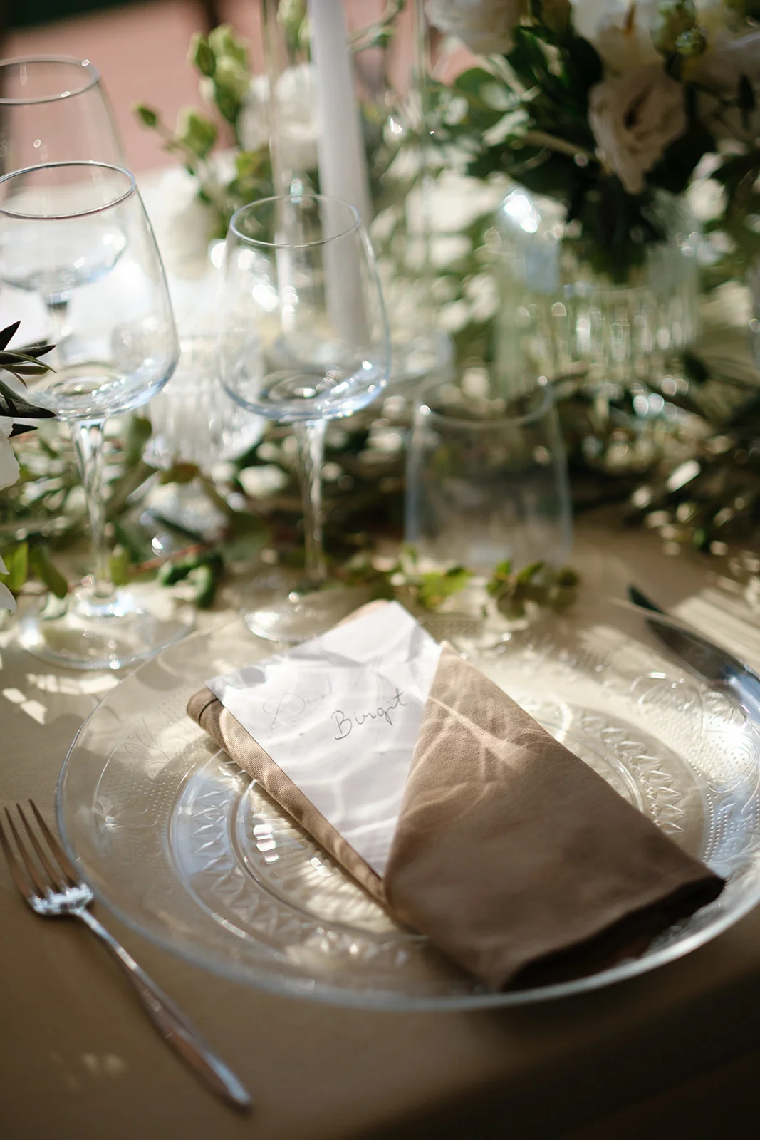 Mise en place con segnaposto calligrafico Mise en place di matrimonio con piatto in vetro lavorato, tovagliolo in lino e segnaposto scritto a mano